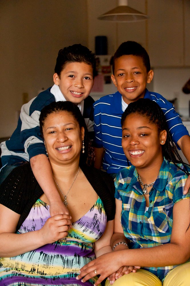 Image of a mother and her three children smiling and looking at the camera. 
