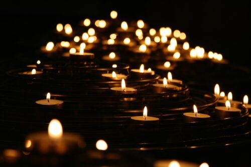 Tea candles for a vigil illuminate a dark room.
